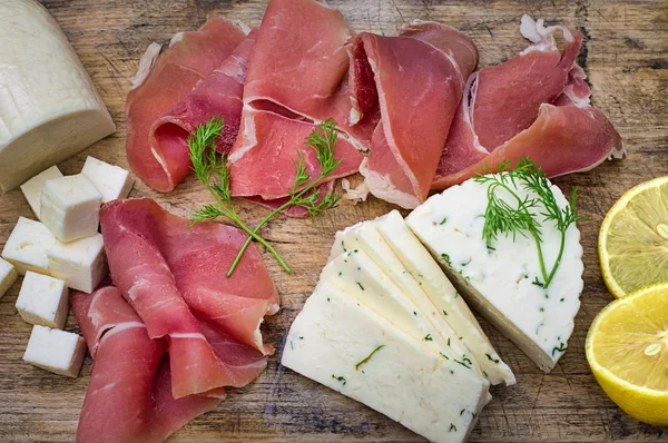 Jamon med olika slags ost på en träskiva. Trä rustik bakgrund. Ovanifrån — Stockfoto