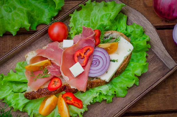 Ciabatta-Sandwich mit Salatblättern, Marmeladenserrano und Mozzarella. Ansicht von oben. Selektiver Fokus. Holz rustikalen Hintergrund — Stockfoto