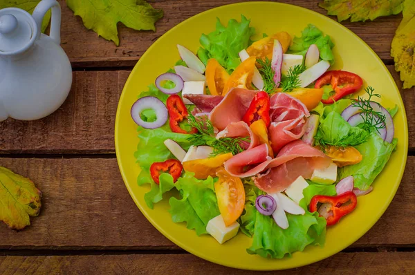 Podzimní salát jamon, hlávkový salát, rajčata, sýr. Dřevěný rustikální pozadí. Selektivní fokus. Pohled shora — Stock fotografie