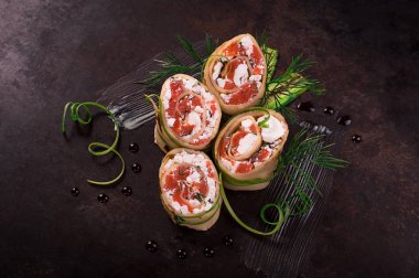 Somon, horseradish krem peynir ile ince krep rulo. Eski siyah arka plan. Üstten Görünüm. Seçici odak