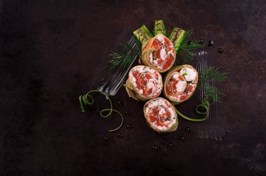 Somon, horseradish krem peynir ile ince krep rulo. Eski siyah arka plan. Üstten Görünüm. Seçici odak