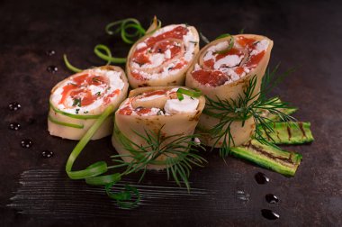 Somon, horseradish krem peynir ile ince krep rulo. Eski siyah arka plan. Üstten Görünüm. Seçici odak