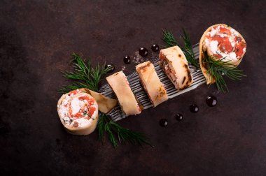 Somon, horseradish krem peynir ile ince krep rulo. Eski siyah arka plan. Üstten Görünüm. Seçici odak