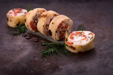 Somon, horseradish krem peynir ile ince krep rulo. Eski siyah arka plan. Üstten Görünüm. Seçici odak