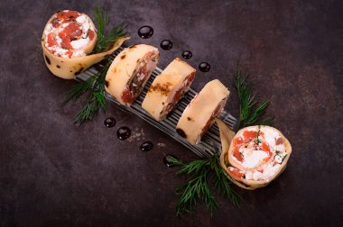 Somon, horseradish krem peynir ile ince krep rulo. Eski siyah arka plan. Üstten Görünüm. Seçici odak