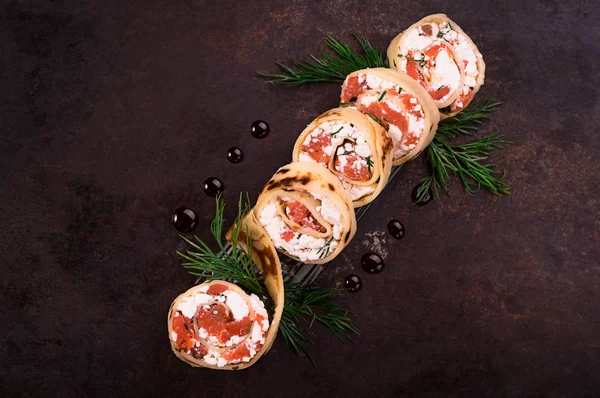 Rollen van dunne pannenkoekjes met zalm, roomkaas van mierikswortel. Zwarte oude achtergrond. Bovenaanzicht. Selectieve aandacht — Stockfoto