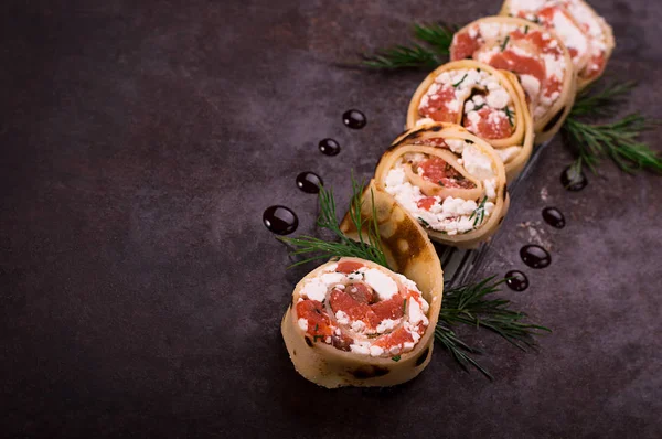 Rollen van dunne pannenkoekjes met zalm, roomkaas van mierikswortel. Zwarte oude achtergrond. Bovenaanzicht. Selectieve aandacht — Stockfoto