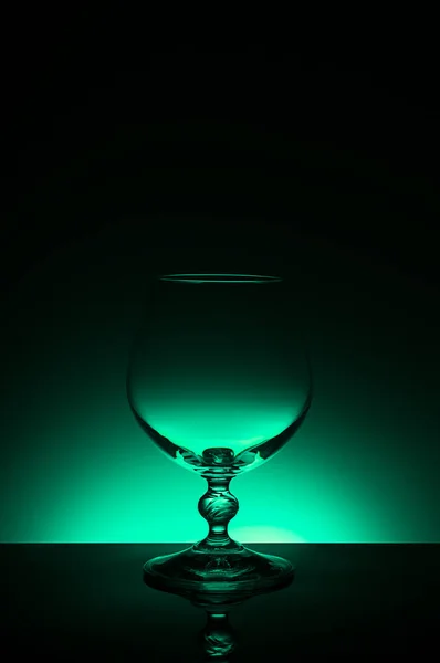 Wineglass on a color background with a black vignette. A tall Wineglass with a thin stalk