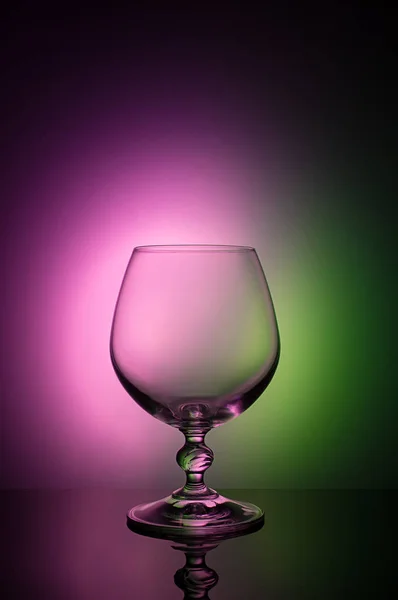 Bicchiere da vino su sfondo a colori con vignetta nera. Un bicchiere di vino alto con un gambo sottile — Foto Stock
