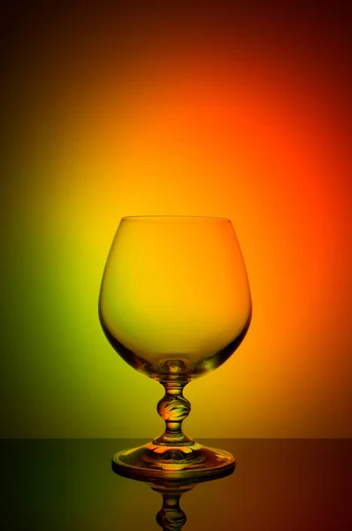 Bicchiere da vino su sfondo a colori con vignetta nera. Un bicchiere di vino alto con un gambo sottile — Foto Stock