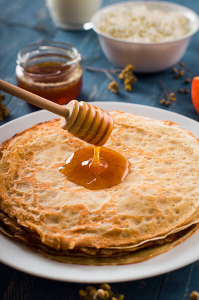 Fresh pancakes with honey, maple syrup, cottage cheese and tangerines. Wooden background. Top view