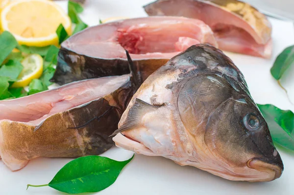 Poisson cru avec légumes verts sur une planche à découper blanche — Photo