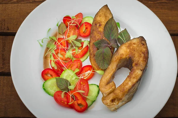 Steak ikan panggang dengan sayuran di atas piring: tomat, microgran, mentimun, makan malam lezat dan sehat. Latar belakang Wooden Rustic. Tampilan atas — Stok Foto
