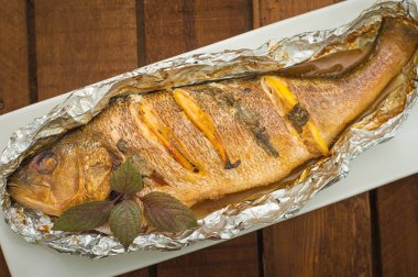 Taze domates, otlar ve limon ile kızarmış balık. Ahşap arka plan. Üstten Görünüm