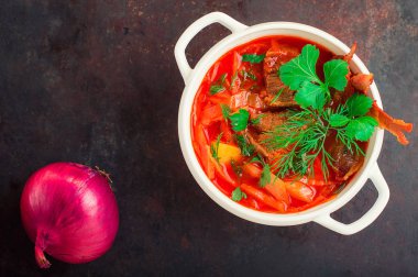 Pancar çorbası et ve beyaz tabakta Yeşiller ile. Geleneksel Ukraynalı Rus kırmızı çorba. Eski siyah rustik geçmiş. Üstten Görünüm