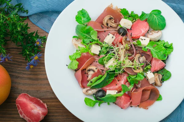 Salat mit Spinat, Käse, Schinken, Grapefruit und Balsamico-Sauce auf ländlichem Holzgrund. Ansicht von oben. Nahaufnahme — Stockfoto