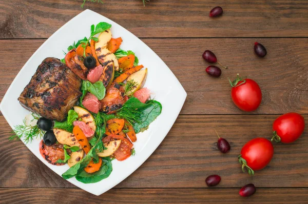 Biefstuk met gegrilde groenten, spinazie en grapefruit met appels. Houten rustieke achtergrond. Bovenaanzicht — Stockfoto