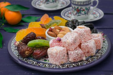 Doğu tatlılar kümesi. Marmelat, kivi, Kuru erik, rahat lokum, fındık, mandalina, Trabzon hurması, Kuru Kayısı, Kuru üzüm bir renkli mavi plaka Antep fıstığı, tarihler. Ahşap rustik arka plan. Üstten Görünüm