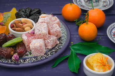 Doğu tatlılar kümesi. Marmelat, kivi, Kuru erik, rahat lokum, fındık, mandalina, Trabzon hurması, Kuru Kayısı, Kuru üzüm bir renkli mavi plaka Antep fıstığı, tarihler. Ahşap rustik arka plan. Üstten Görünüm