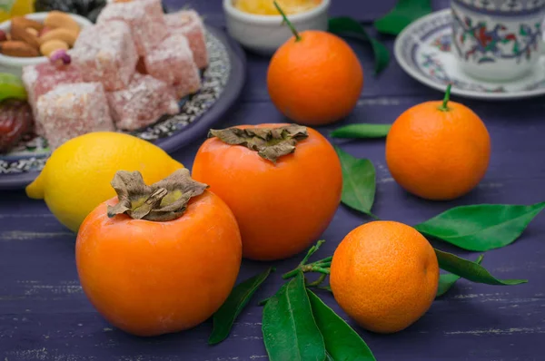 Fruchtansatz. Mandarinen, Kaki, Zitrone mit orientalischen Süßigkeiten, Rahat Lokum. Selektiver Fokus. Holz blau rustikalen Hintergrund. Ansicht von oben — Stockfoto