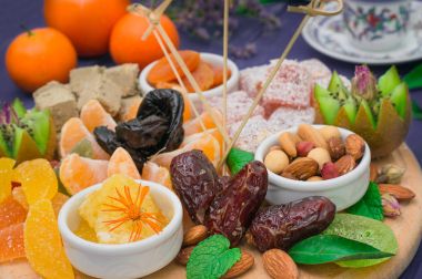 Doğu tatlılar kümesi. Marmelat, kivi, Kuru erik, rahat lokum, fındık, mandalina, Trabzon hurması, Kuru Kayısı, Antep fıstığı, tarihler, mavi renkli bir üzüm. Ahşap rustik arka plan. Üstten Görünüm