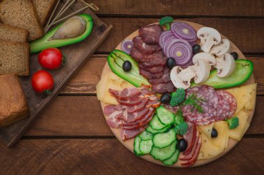 Jambon, salam, pastırma, domuz eti, peynir, mantar, salatalık, ekmek, avokado, soğan ve zeytin soğuk füme et. Ahşap rustik arka plan. Üstten Görünüm