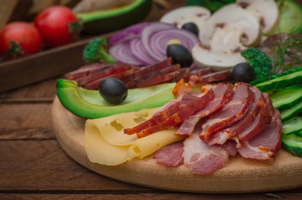 Kallrökt kött med prosciutto, salami, bacon, Fläskkotletter, ost, svamp, gurka, bröd, avokado, lök och Oliver. Trä rustik bakgrund. Ovanifrån — Stockfoto