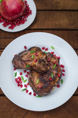 Narlı beyaz bir plaka üzerinde bir ızgarada pişmiş pirzola, biftek. Ahşap rustik arka plan. Üstten Görünüm