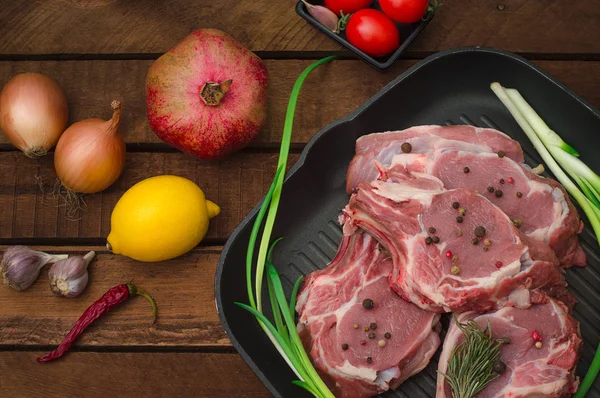 Ingredience pro vaření žebra eye pečené hovězí steak na černé železné grilovací pánev. Dřevěný rustikální pozadí. Pohled shora, horizontální kompozice — Stock fotografie