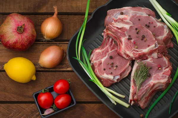 Hozzávalókat főzés rib eye sült marha steak fekete vas grillezés pan. Rusztikus fa háttér. Felülnézet, vízszintes összetétele — Stock Fotó