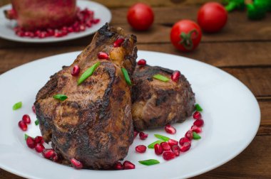 Narlı beyaz bir plaka üzerinde bir ızgarada pişmiş pirzola, biftek. Ahşap rustik arka plan. Üstten Görünüm