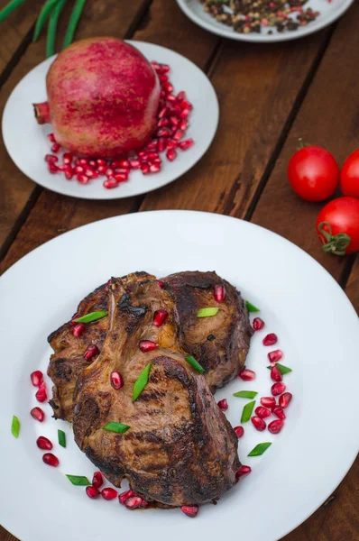 Narlı beyaz bir plaka üzerinde bir ızgarada pişmiş pirzola, biftek. Ahşap rustik arka plan. Üstten Görünüm