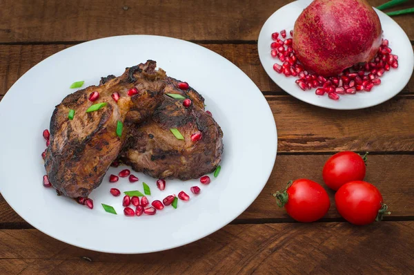 Narlı beyaz bir plaka üzerinde bir ızgarada pişmiş pirzola, biftek. Ahşap rustik arka plan. Üstten Görünüm