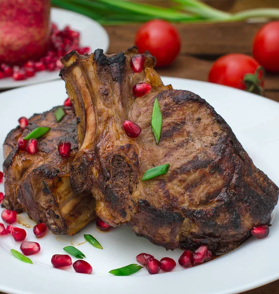 Narlı beyaz bir plaka üzerinde bir ızgarada pişmiş pirzola, biftek. Ahşap rustik arka plan. Üstten Görünüm