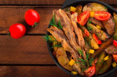 Pastırma ve tavada taze domates ile kızarmış patates. Ahşap rustik arka plan. Üstten Görünüm