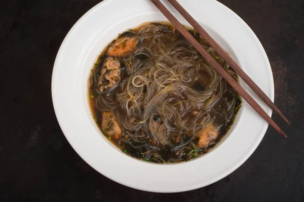 Cuisine japonaise, soupe au porc chashu, ciboulette, choux, nouilles et algues sur la table sous la lumière du soleil. Vieux fond rustique noir. Vue du dessus — Photo