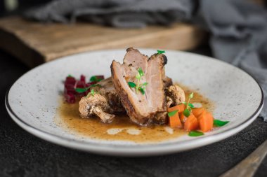 Domuz kaburga pancar, havuç, kızarmış yağlı mantar ve beyaz tabakta sos ile. Restoran hizmet. Eski siyah rustik geçmiş. Üstten Görünüm