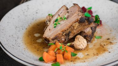 Domuz kaburga pancar, havuç, kızarmış yağlı mantar ve beyaz tabakta sos ile. Restoran hizmet. Eski siyah rustik geçmiş. Üstten Görünüm