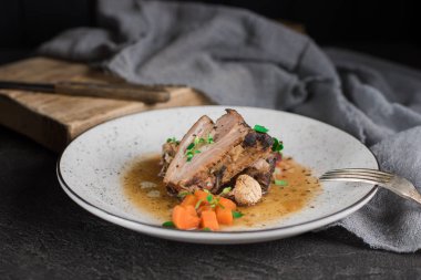 Domuz kaburga pancar, havuç, kızarmış yağlı mantar ve beyaz tabakta sos ile. Restoran hizmet. Eski siyah rustik geçmiş. Üstten Görünüm