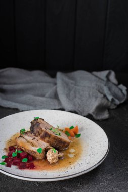 Domuz kaburga pancar, havuç, kızarmış yağlı mantar ve beyaz tabakta sos ile. Restoran hizmet. Eski siyah rustik geçmiş. Üstten Görünüm