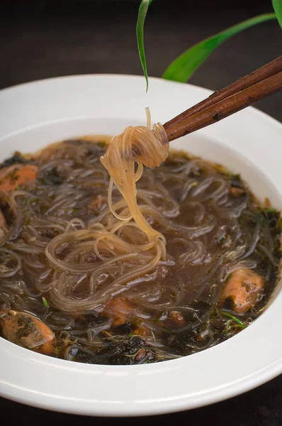 Cucina giapponese, zuppa di maiale chashu, erba cipollina, germogli, tagliatelle e alghe sul tavolo sotto la luce del sole. Vecchio sfondo nero rustico. Vista dall'alto — Foto Stock