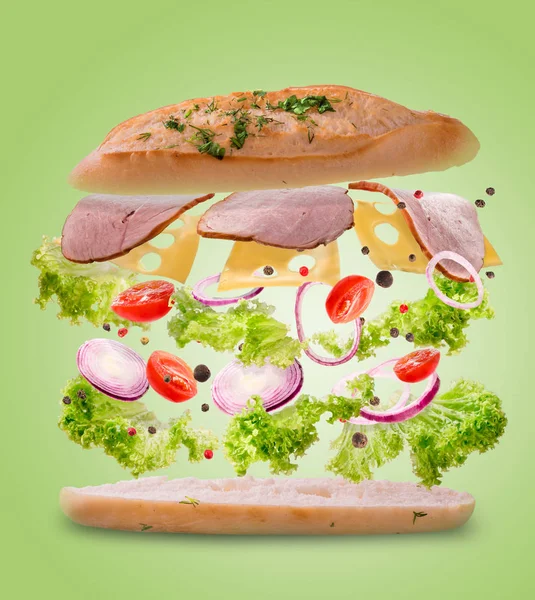 Sandwich mit fliegenden Zutaten. Bewegung einfrieren. Nahaufnahme. lindgrüner Hintergrund. — Stockfoto
