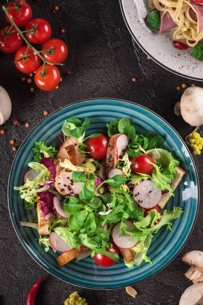 Frischer Gemüsesalat mit gegrillter Hühnerbrust - Tomaten, Rettich und gemischte Salatblätter. Hühnersalat. Gesunde Ernährung. schwarzer Hintergrund. Ansicht von oben — Stockfoto