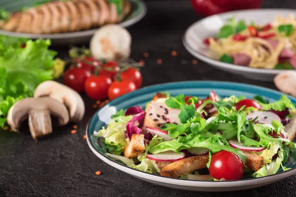 Fresh vegetable salad with grilled chicken breast - tomatoes, radish and mix lettuce leaves. Chicken salad. Healthy food. Black background. Top view — Stock Photo, Image