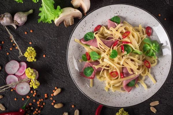 Italian spaghetti. Tagliatelle pasta with ham. Selective focus. Black background. Top view — Stock Photo, Image