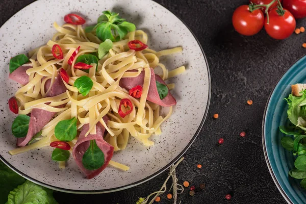 Italian spaghetti. Tagliatelle pasta with ham. Selective focus. Black background. Top view — Stock Photo, Image