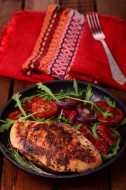 Roka ve siyah bir tavada sebze yeşil salata ile ızgara tavuk göğsü. Ahşap rustik arka plan. Üstten Görünüm