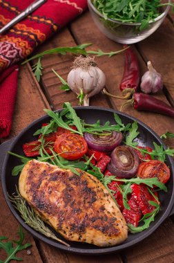 Roka ve siyah bir tavada sebze yeşil salata ile ızgara tavuk göğsü. Ahşap rustik arka plan. Üstten Görünüm