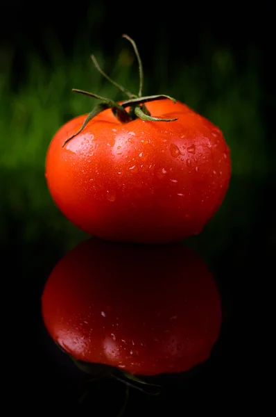Tomato isolated on the black and glossy background with realistic reflection and water drops — Stock Photo, Image