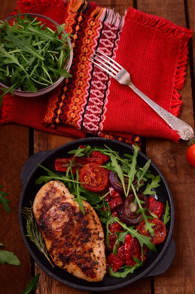 Gegrilde kippenborst met groene salade van rucola en fruit op een zwarte pan. Houten rustieke achtergrond. Bovenaanzicht — Stockfoto